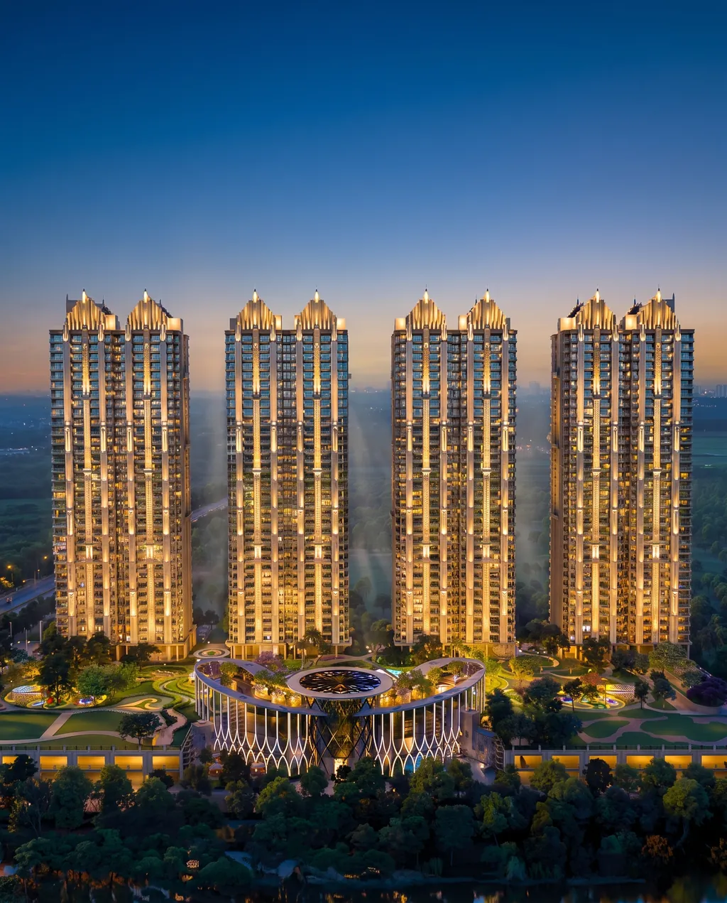 Gaur Alaris art-deco-crowned towers lit at blue hour, the clubhouse and landscaped grounds at their base (builder render, artistic visualization)